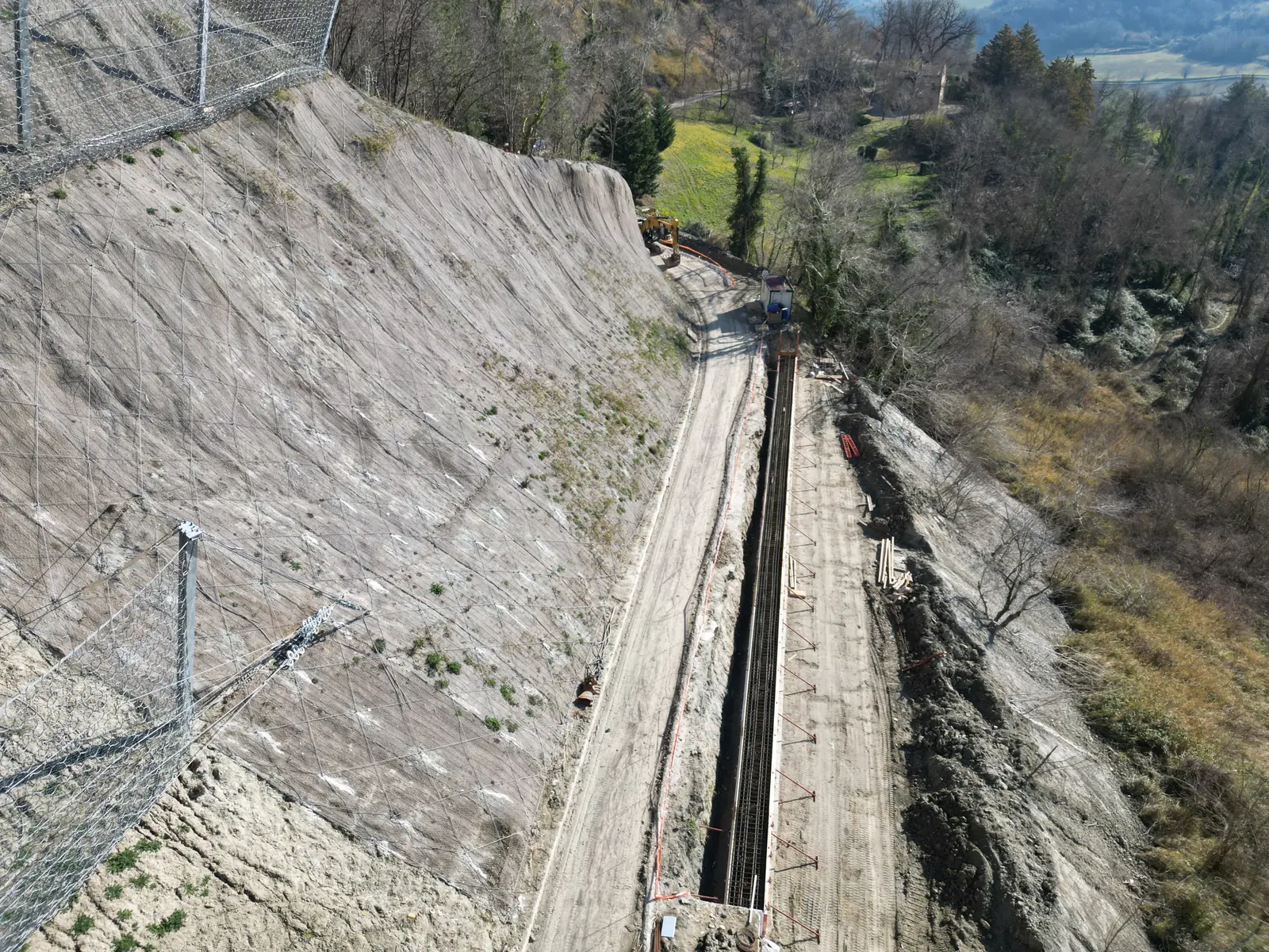 Canaletta in calcestruzzo lungo la strada al piede di una scarpata consolidata, vista dall’alto