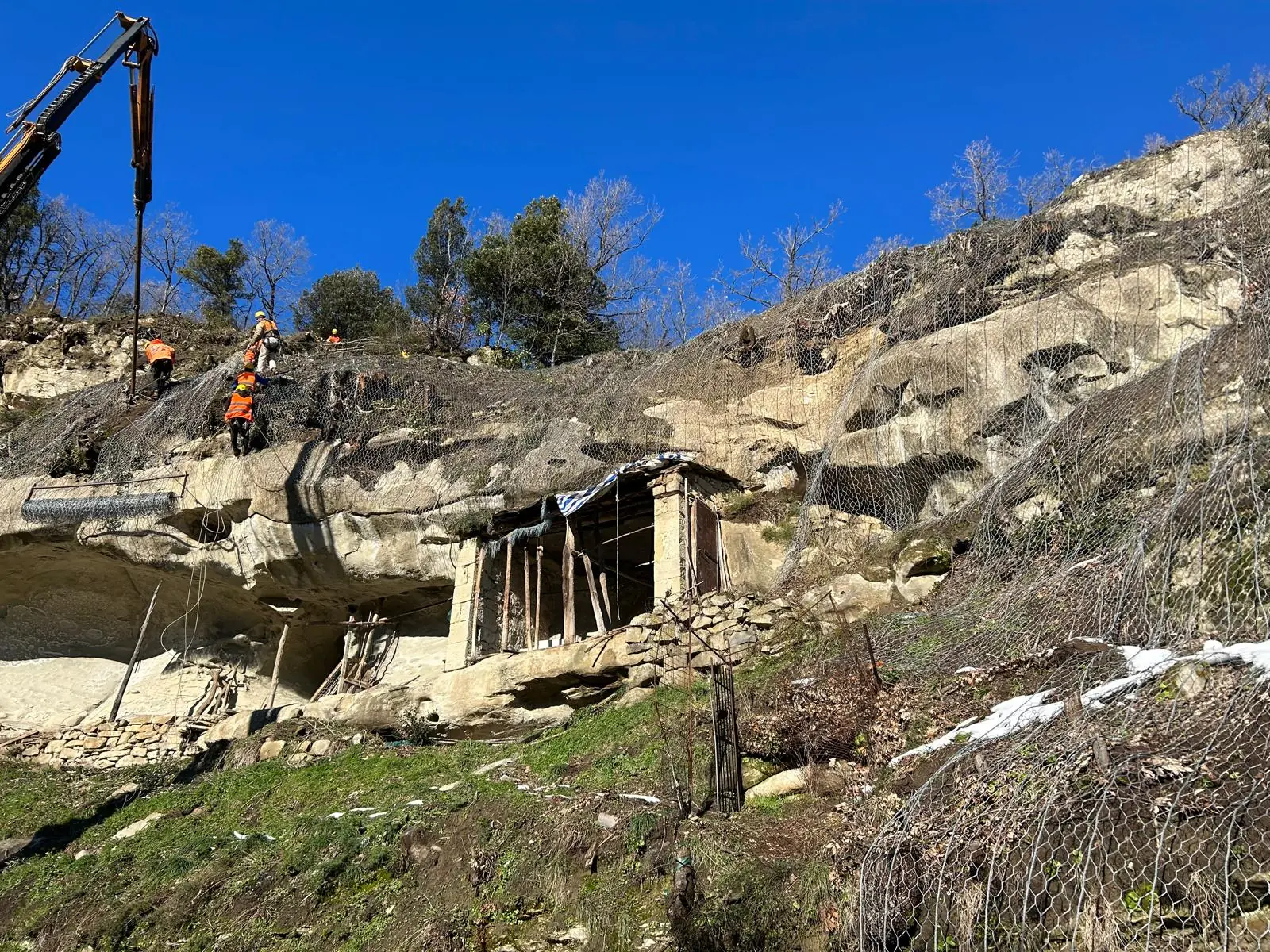 Operatore su cestello di autogru al lavoro su una parete rocciosa