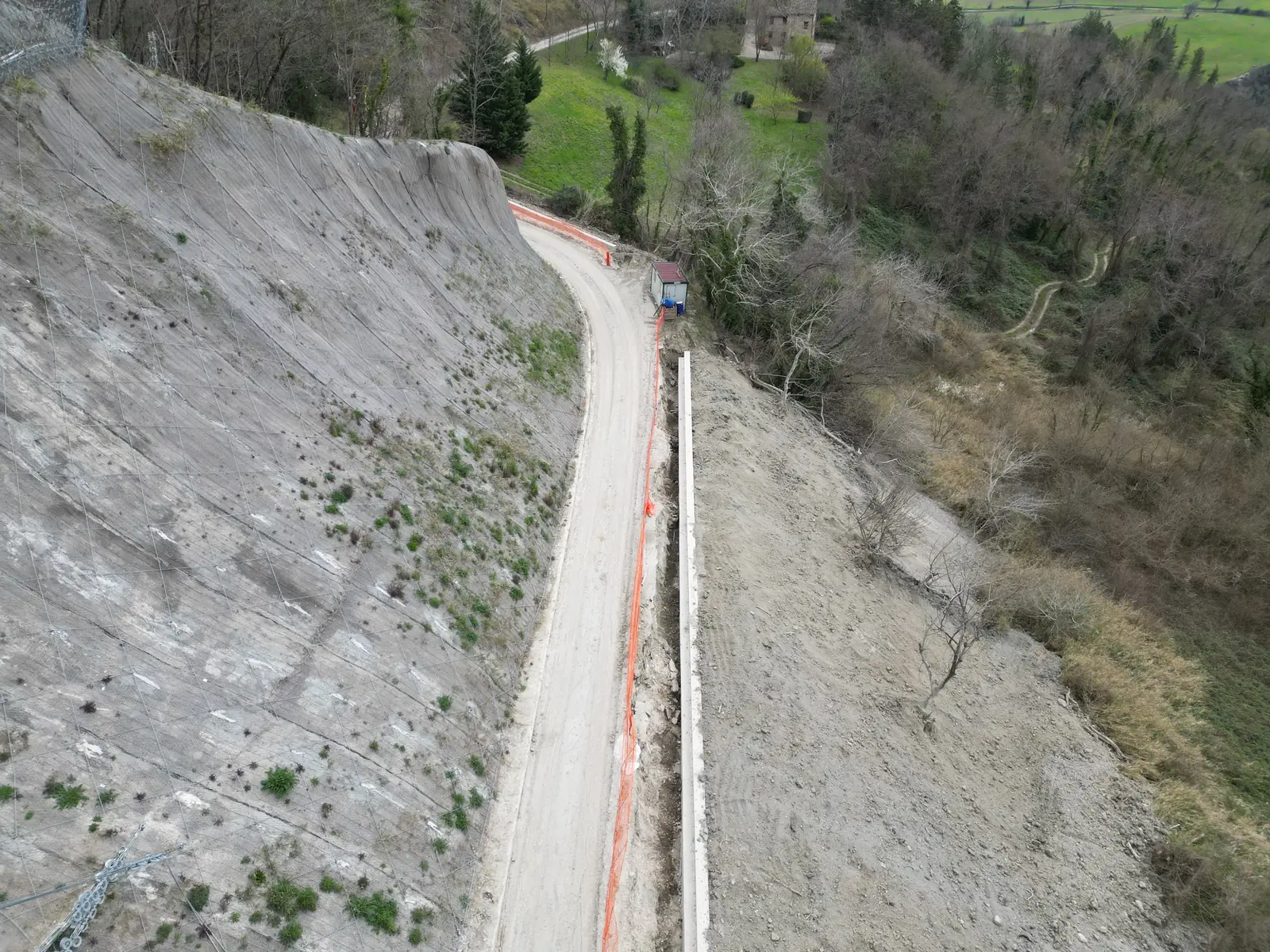 Strada di montagna ripristinata ai piedi di un versante protetto da rete e barriere
